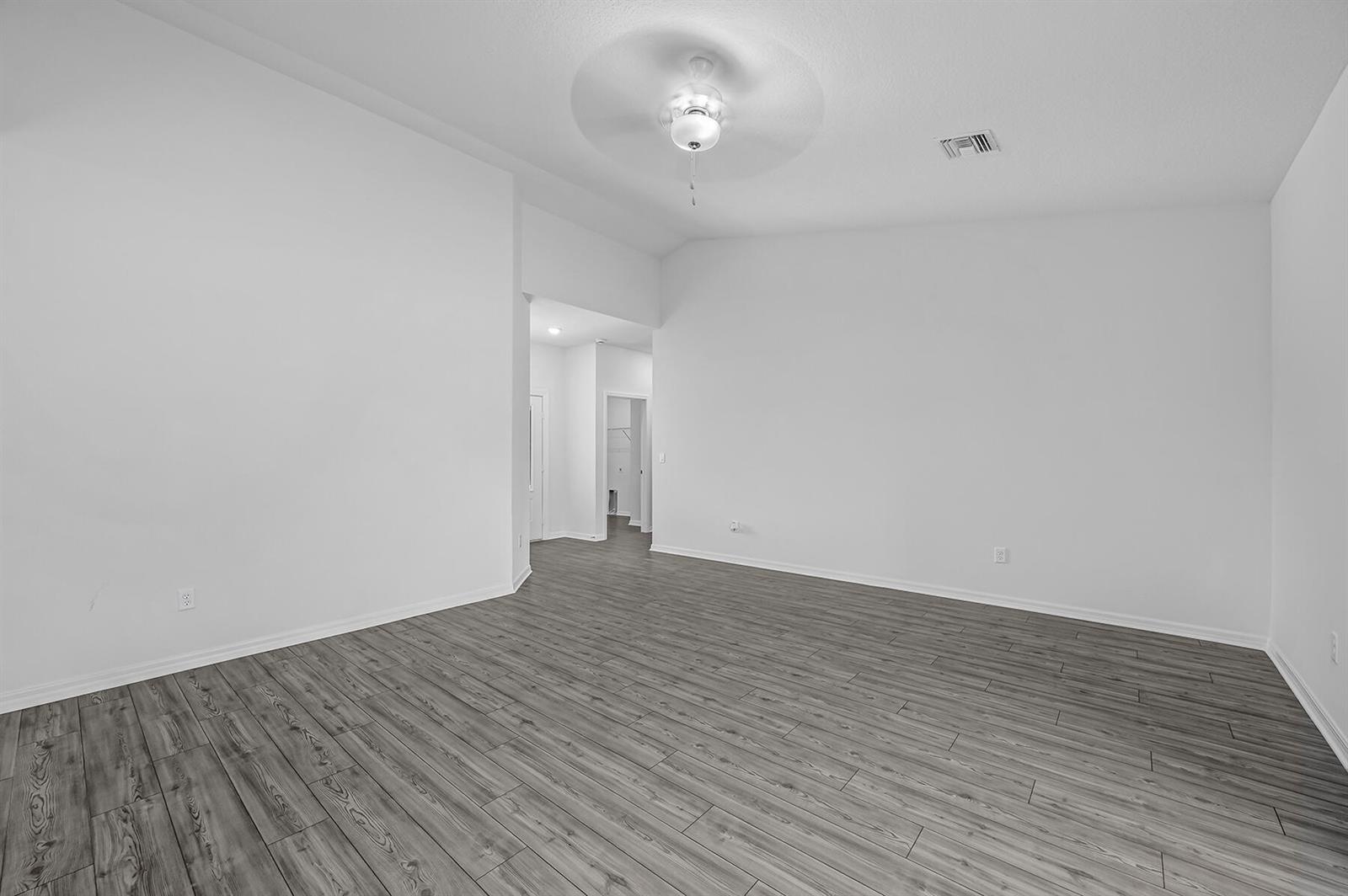 An empty room with white walls, gray wood-look flooring, and a ceiling fan — 7945 105th Court, Vero Beach FL 32967, VERO BEACH, FL