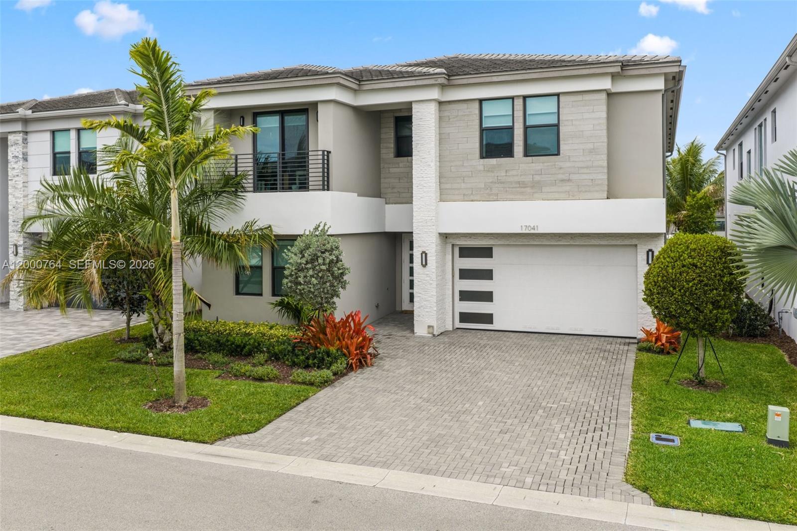 A two-story modern house features a paved driveway, a white garage door, and a balcony — 17041 Teton River Rd, Boca Raton FL 33496, BOCA RATON, FL