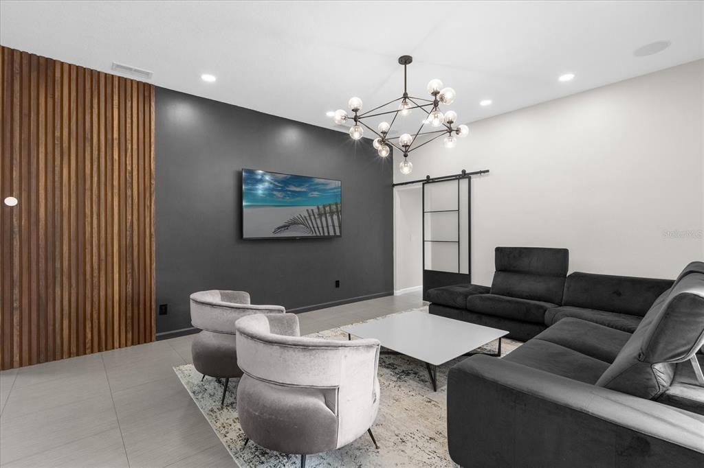 A modern living room features a dark accent wall, wood slat paneling, and a chandelier — 10175 COVE LAKE DRIVE, ORLANDO, FL