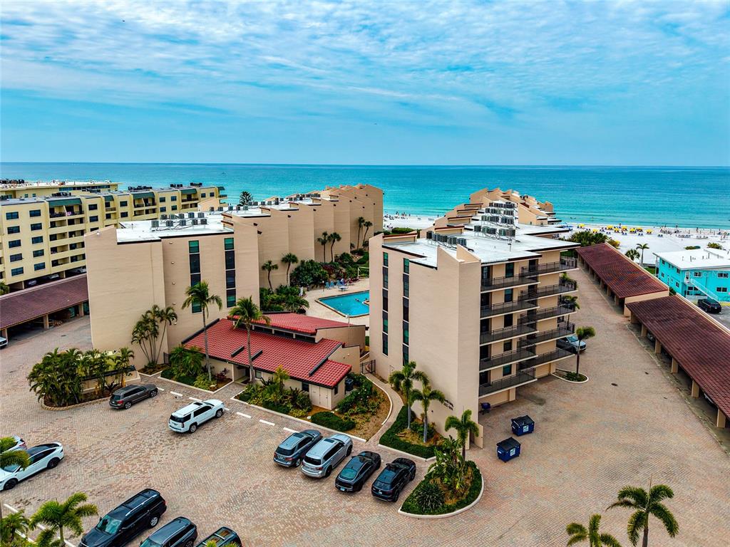 An aerial view shows a multi-story apartment complex with a pool near the ocean — 6480 MIDNIGHT PASS ROAD UNIT 503, SARASOTA, FL