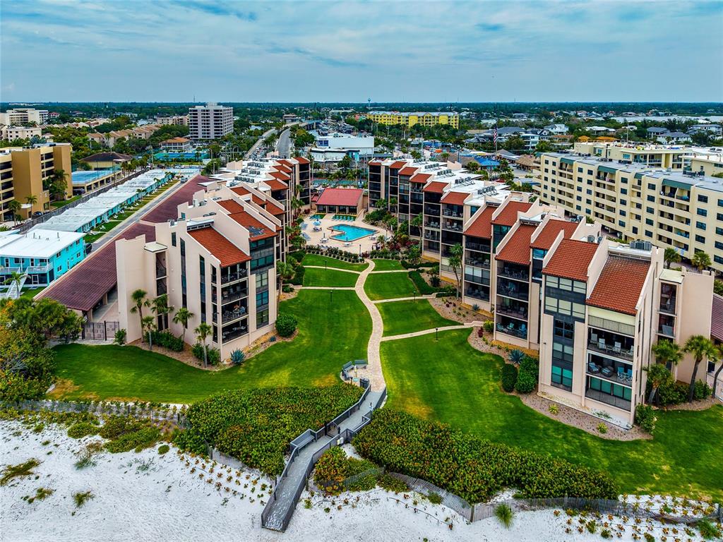 An aerial view shows a multi-story apartment complex with a pool, lawn, and beach access — 6480 MIDNIGHT PASS ROAD UNIT 503, SARASOTA, FL