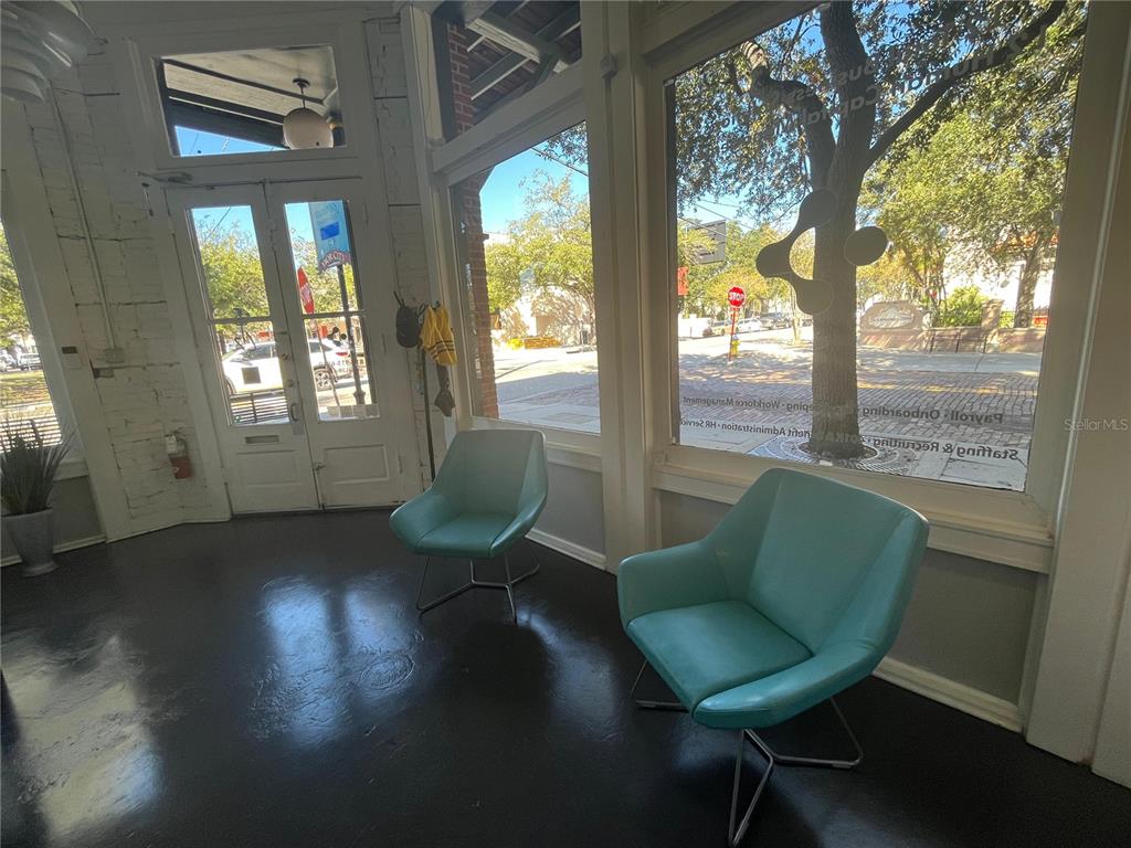 A bright room with two teal chairs, large windows, and a view of a street — 1501 E 9TH AVENUE UNIT A, TAMPA, FL