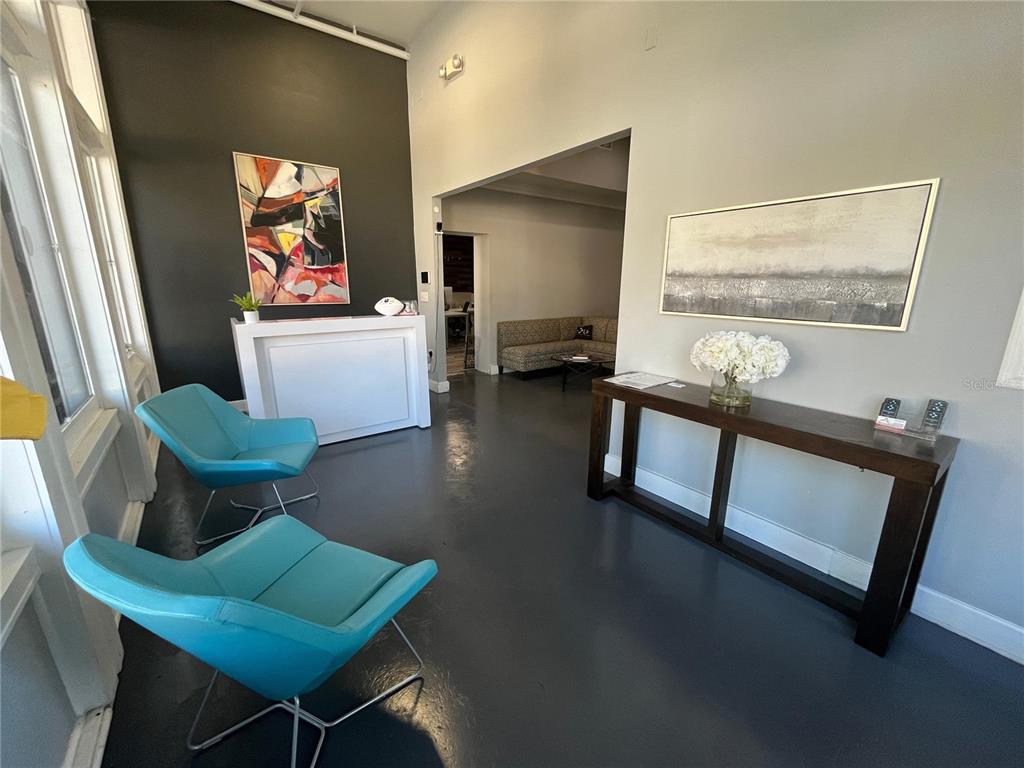 A waiting area features two blue chairs, a reception desk, and a dark wood console table — 1501 E 9TH AVENUE UNIT A, TAMPA, FL