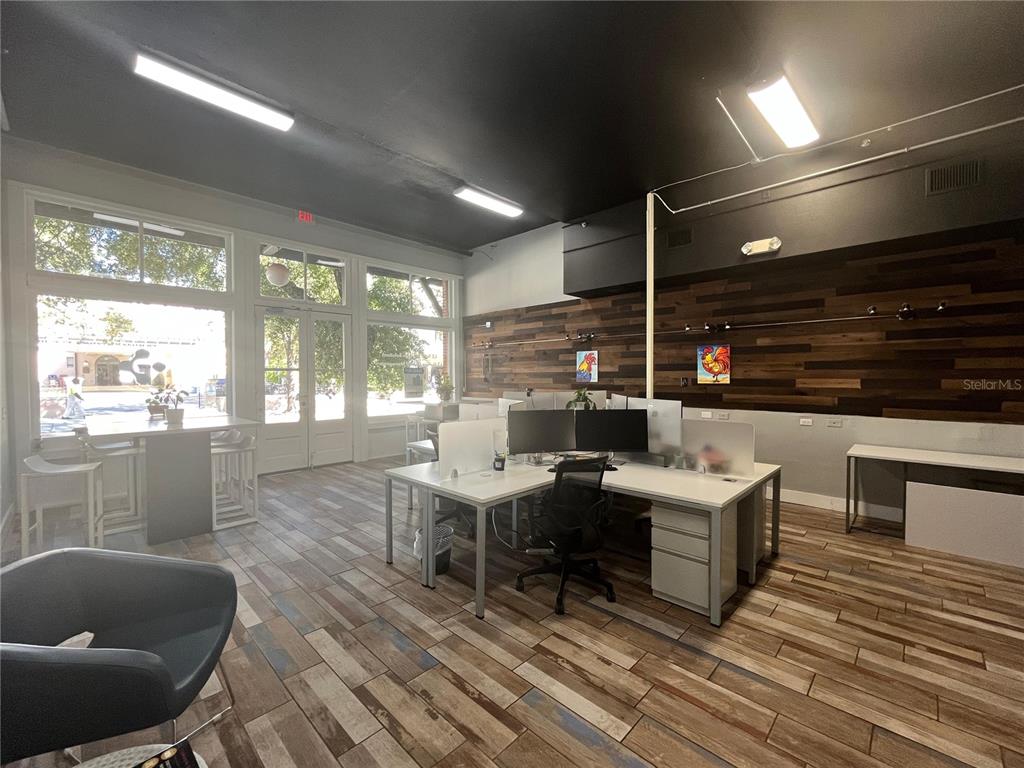 An office space features wood-look tile flooring, a wood-paneled accent wall, and a central workstation — 1501 E 9TH AVENUE UNIT A, TAMPA, FL