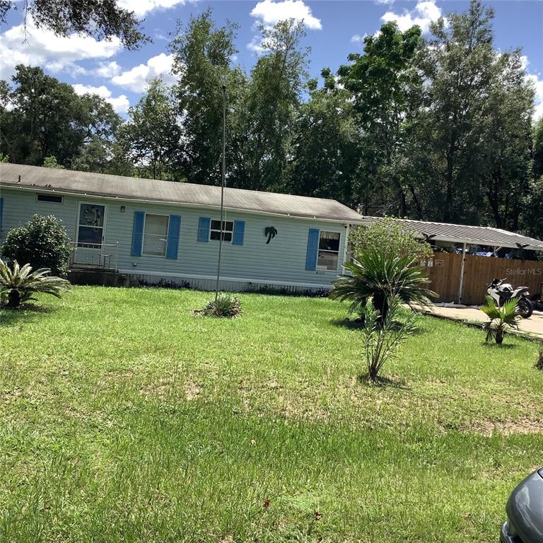 A light blue single-wide mobile home with blue shutters and a metal carport — 20406 BLUE WING ROAD, ALTOONA, FL