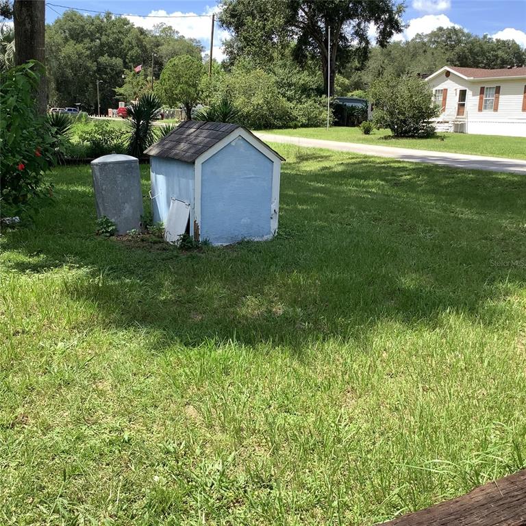 A small blue shed and a metal tank sit in a grassy yard — 20406 BLUE WING ROAD, ALTOONA, FL