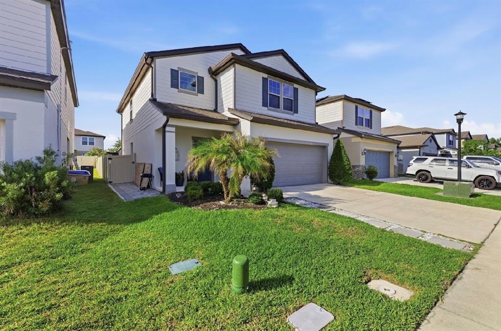 A two-story suburban house with a gray garage, a palm tree, and a grassy lawn — 3557 ROCK CREEK LANE, KISSIMMEE, FL