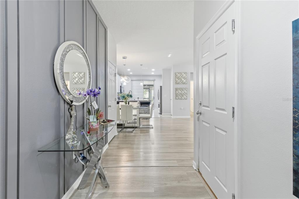 An entryway with light wood flooring, a glass console table, and a circular wall mirror — 3557 ROCK CREEK LANE, KISSIMMEE, FL
