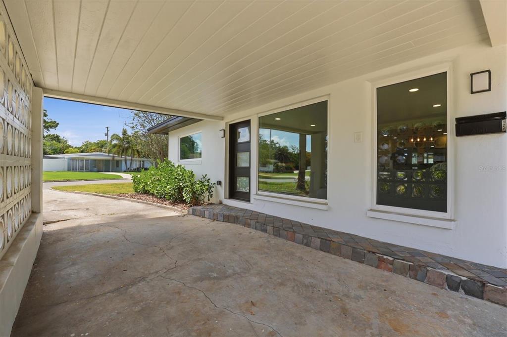 A covered concrete carport leads to a front entrance with a modern door and windows — 628 ONTARIO AVENUE, TAMPA, FL