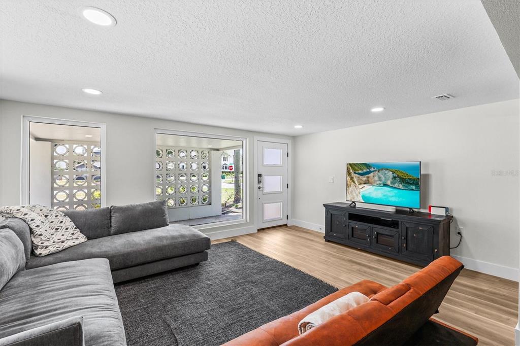 A living room features a gray sectional, an orange sofa, wood flooring, and decorative breeze blocks — 628 ONTARIO AVENUE, TAMPA, FL