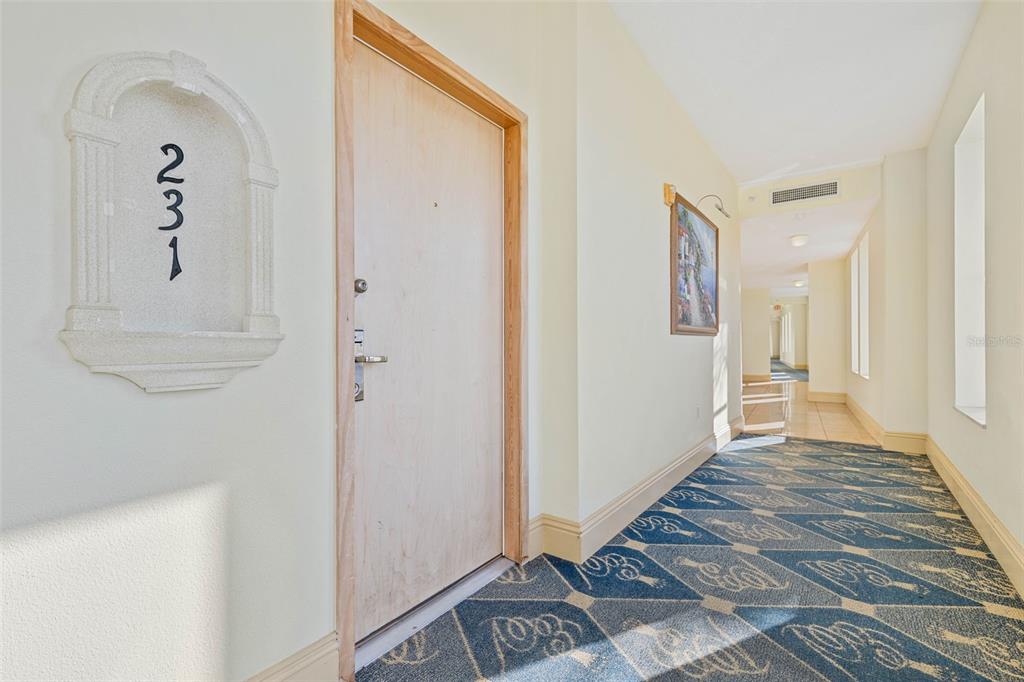 A hallway features a door labeled 231, patterned blue carpet, and light-colored walls — 101 PALM HARBOR PARKWAY UNIT C231, PALM COAST, FL