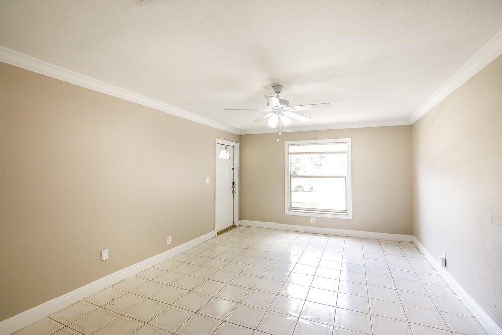 An empty room with beige walls, white tile flooring, a ceiling fan, and a window — LAUDERHILL, FL