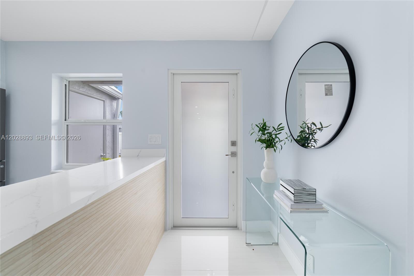 A light-filled entryway features a glass console table, a round mirror, and a frosted door — 18555 Egret Way, Boca Raton FL 33496, BOCA RATON, FL
