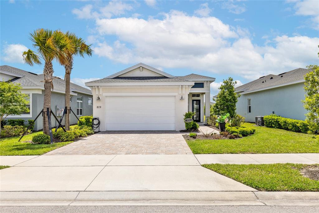 A single-story house with a white garage, paved driveway, and palm trees in the front — 819 LILIANA DRIVE, DELAND, FL