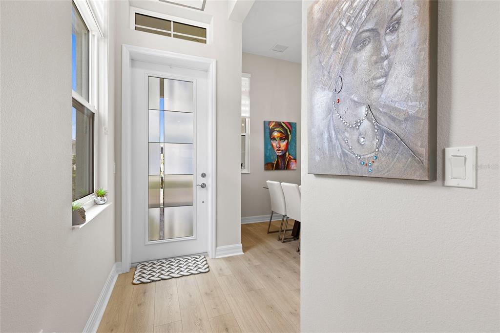 An entryway features a white front door with glass panels, light wood floors, and artwork — 819 LILIANA DRIVE, DELAND, FL