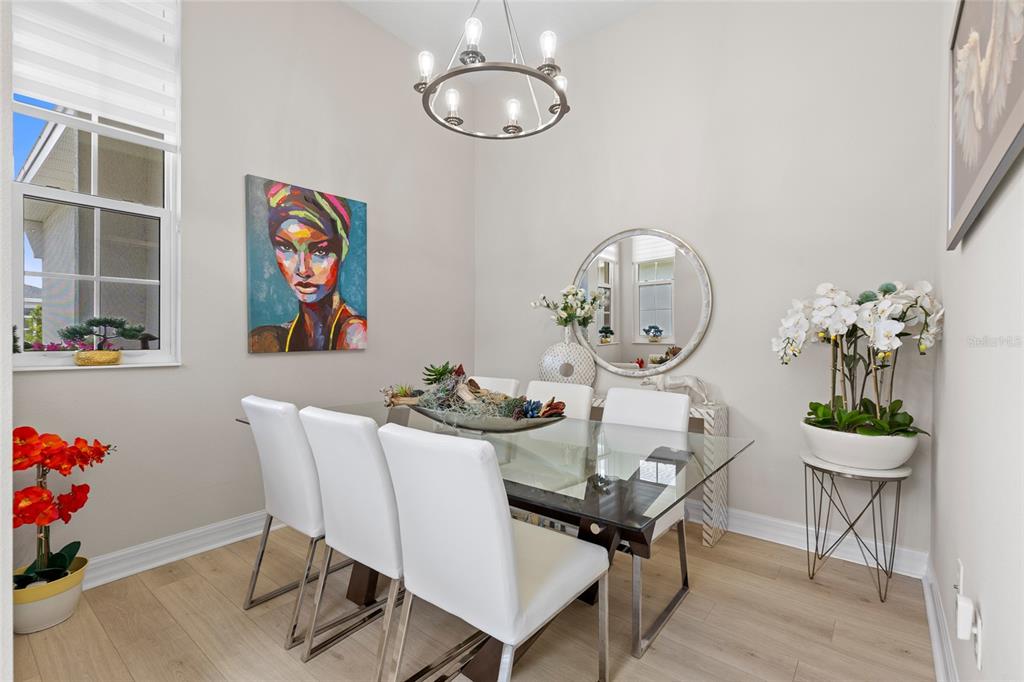A dining room features a glass-topped table, white chairs, a round mirror, and wall art — 819 LILIANA DRIVE, DELAND, FL