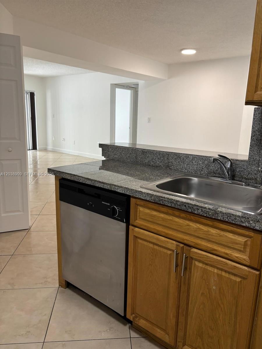 A kitchen features a stainless steel dishwasher, granite countertops, and light wood cabinets — 6276 NW 186th St # 204, Hialeah FL 33015, HIALEAH, FL