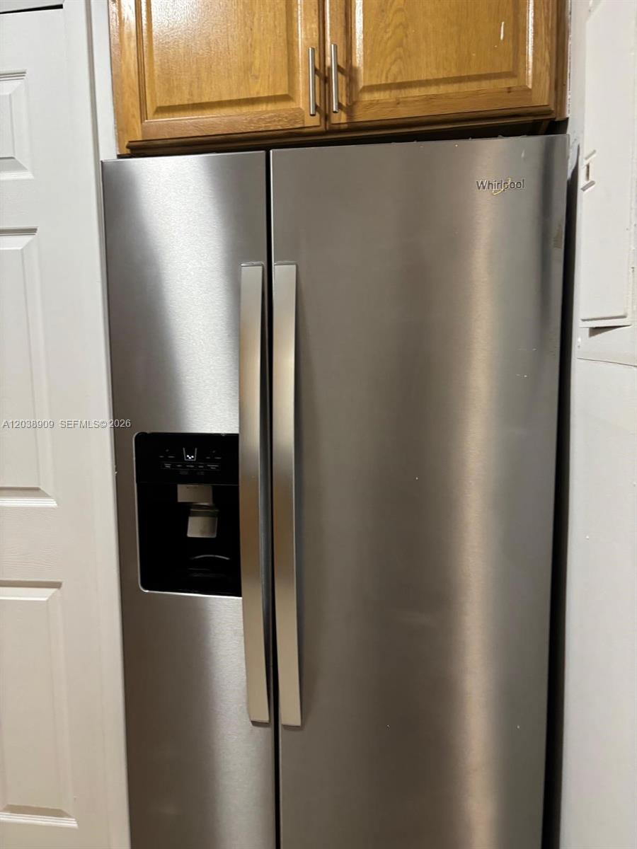 A stainless steel side-by-side refrigerator is positioned beneath wooden kitchen cabinets — 6276 NW 186th St # 204, Hialeah FL 33015, HIALEAH, FL