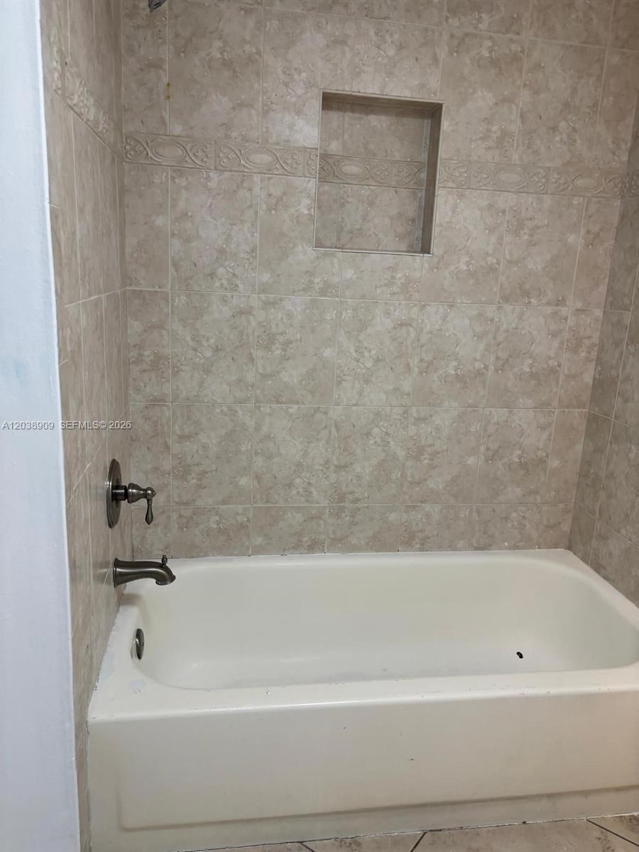 A bathtub with a shower faucet and a recessed wall niche is tiled in beige — 6276 NW 186th St # 204, Hialeah FL 33015, HIALEAH, FL