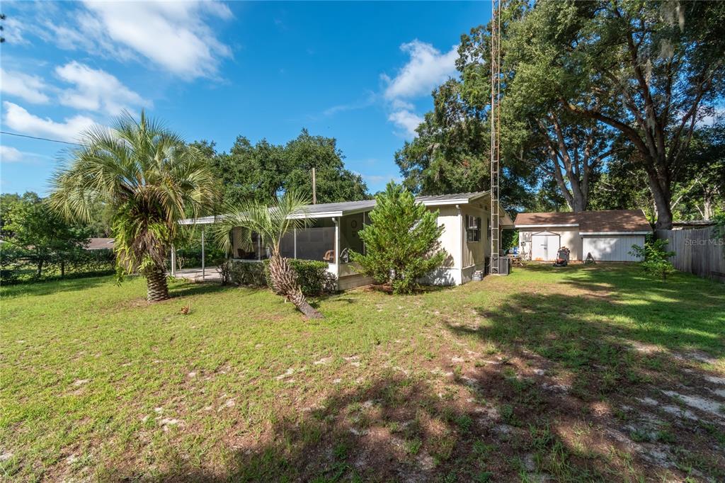 A single-story house with a screened porch, a detached garage, and a large grassy yard — 5888 SE 164TH AVENUE, OCKLAWAHA, FL