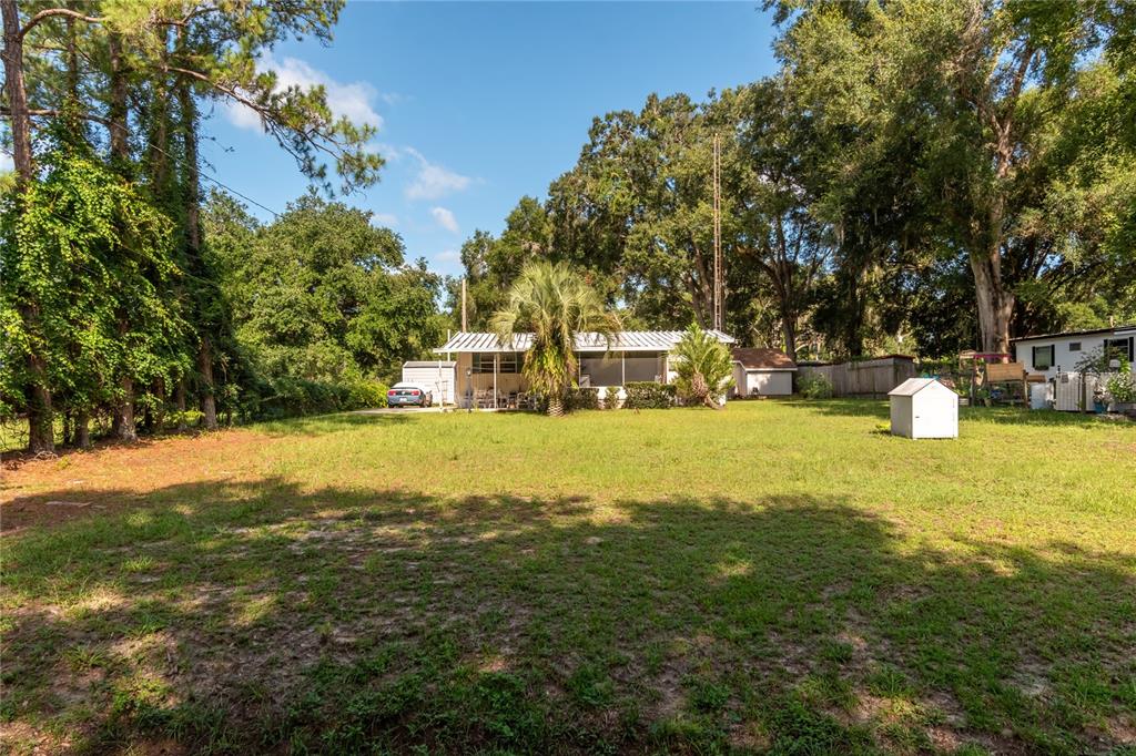 A single-story house with a screened porch sits in a large, grassy, tree-lined yard — 5888 SE 164TH AVENUE, OCKLAWAHA, FL