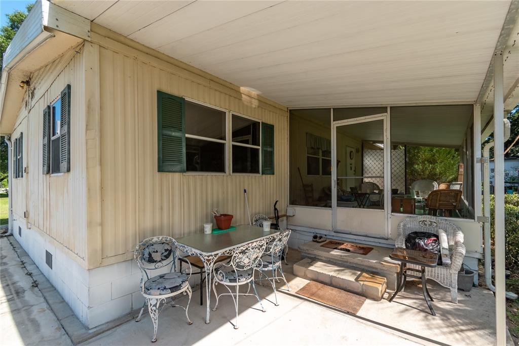 A patio area with a table, chairs, and a screened-in porch entrance on a mobile home — 5888 SE 164TH AVENUE, OCKLAWAHA, FL