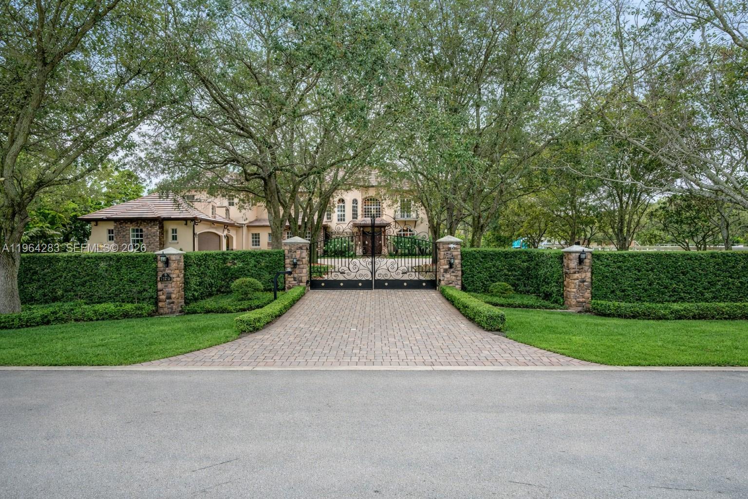 A gated driveway leads to a large two-story house surrounded by mature trees and hedges — 12270 SW 45th St, Miami FL 33175, MIAMI, FL