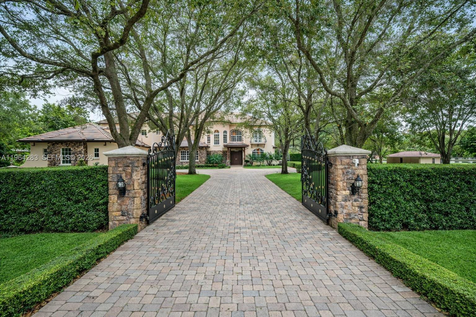 A paved driveway leads through an open gate toward a large two-story house — 12270 SW 45th St, Miami FL 33175, MIAMI, FL