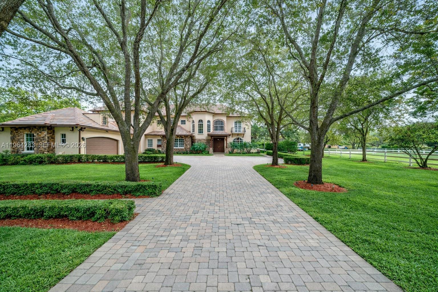 A large two-story house with a stone facade and a paved driveway sits among trees — 12270 SW 45th St, Miami FL 33175, MIAMI, FL