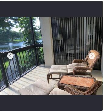 A screened-in balcony features wicker lounge chairs overlooking a pond and walking path — 2025 Lavers Circle # D206, Delray Beach FL 33444, DELRAY BEACH, FL