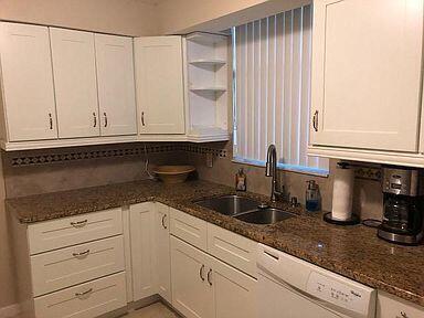 A kitchen features white cabinets, granite countertops, a double sink, and a dishwasher — 2025 Lavers Circle # D206, Delray Beach FL 33444, DELRAY BEACH, FL