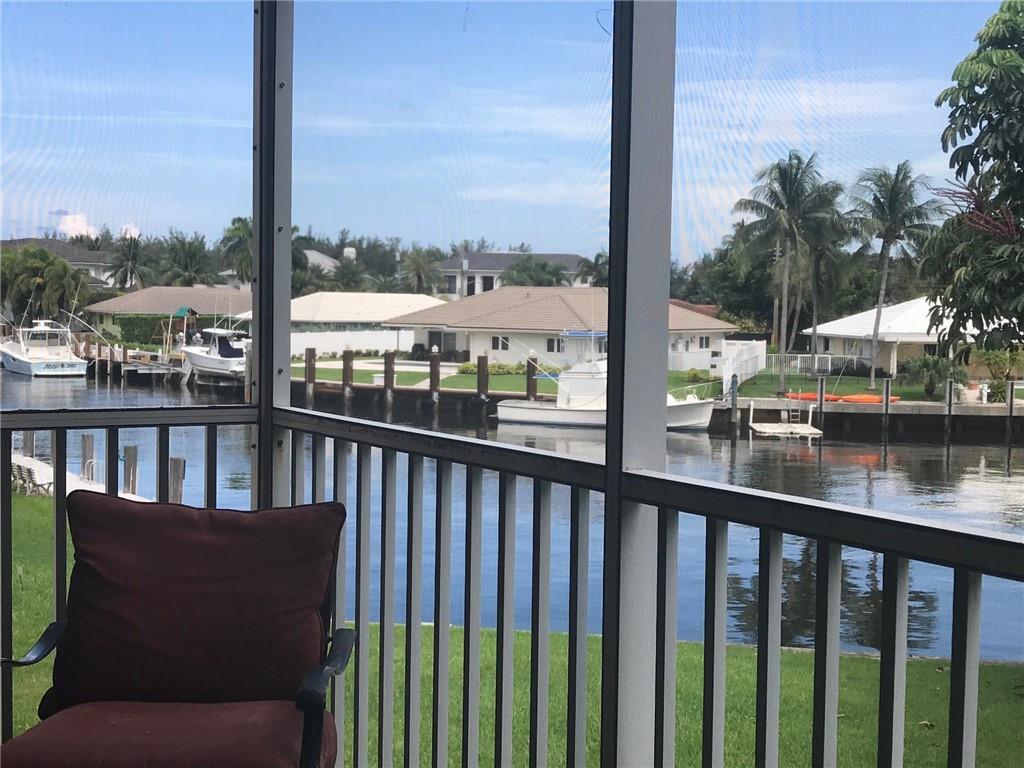 A view from a screened-in porch overlooking a canal with docked boats and houses — 698 NE Spanish River Boulevard # 0250, Boca Raton FL 33431, BOCA RATON, FL