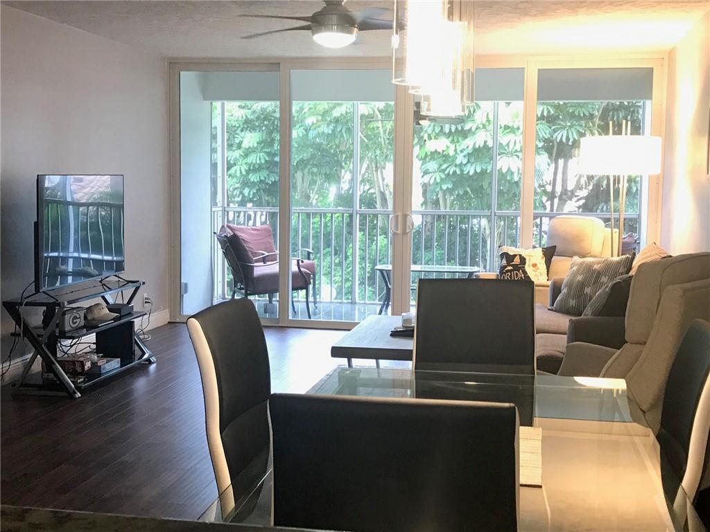 A living and dining area features dark wood floors, a glass table, and a balcony — 698 NE Spanish River Boulevard # 0250, Boca Raton FL 33431, BOCA RATON, FL