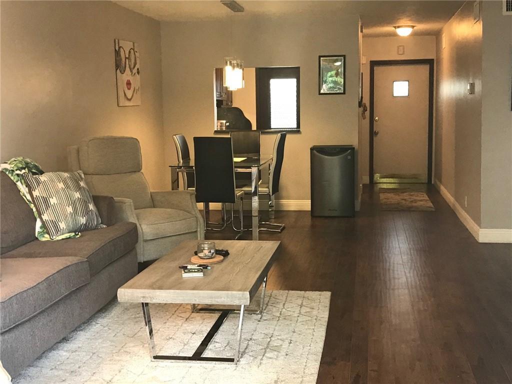 A living room and dining area with dark wood floors, a grey sofa, and furniture — 698 NE Spanish River Boulevard # 0250, Boca Raton FL 33431, BOCA RATON, FL
