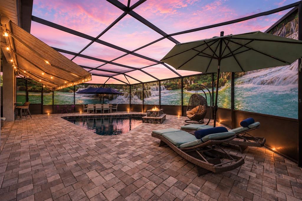 A screened-in pool patio features a fire pit, lounge chairs, and a waterfall mural — 1500 W ALTON BAY PLACE, HERNANDO, FL