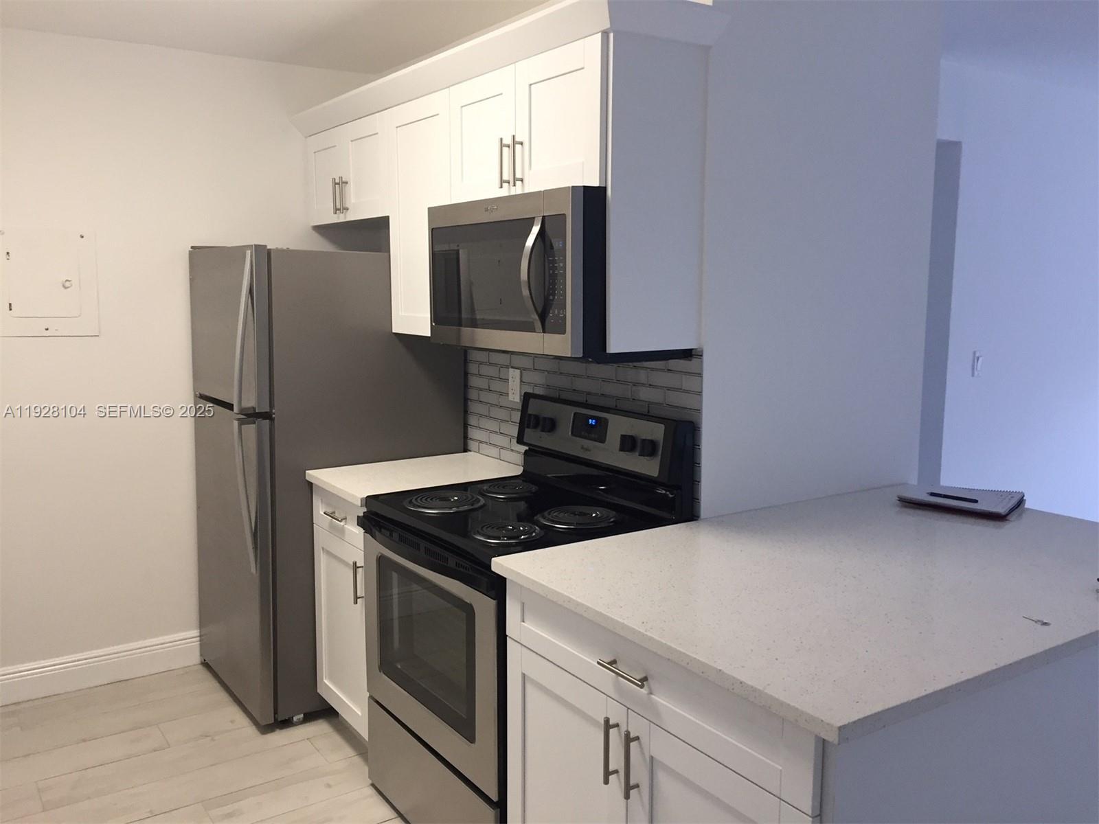A kitchen features white cabinets, stainless steel appliances, and light-colored quartz countertops — 10740 N Kendall Dr # 24, Miami FL 33176, MIAMI, FL