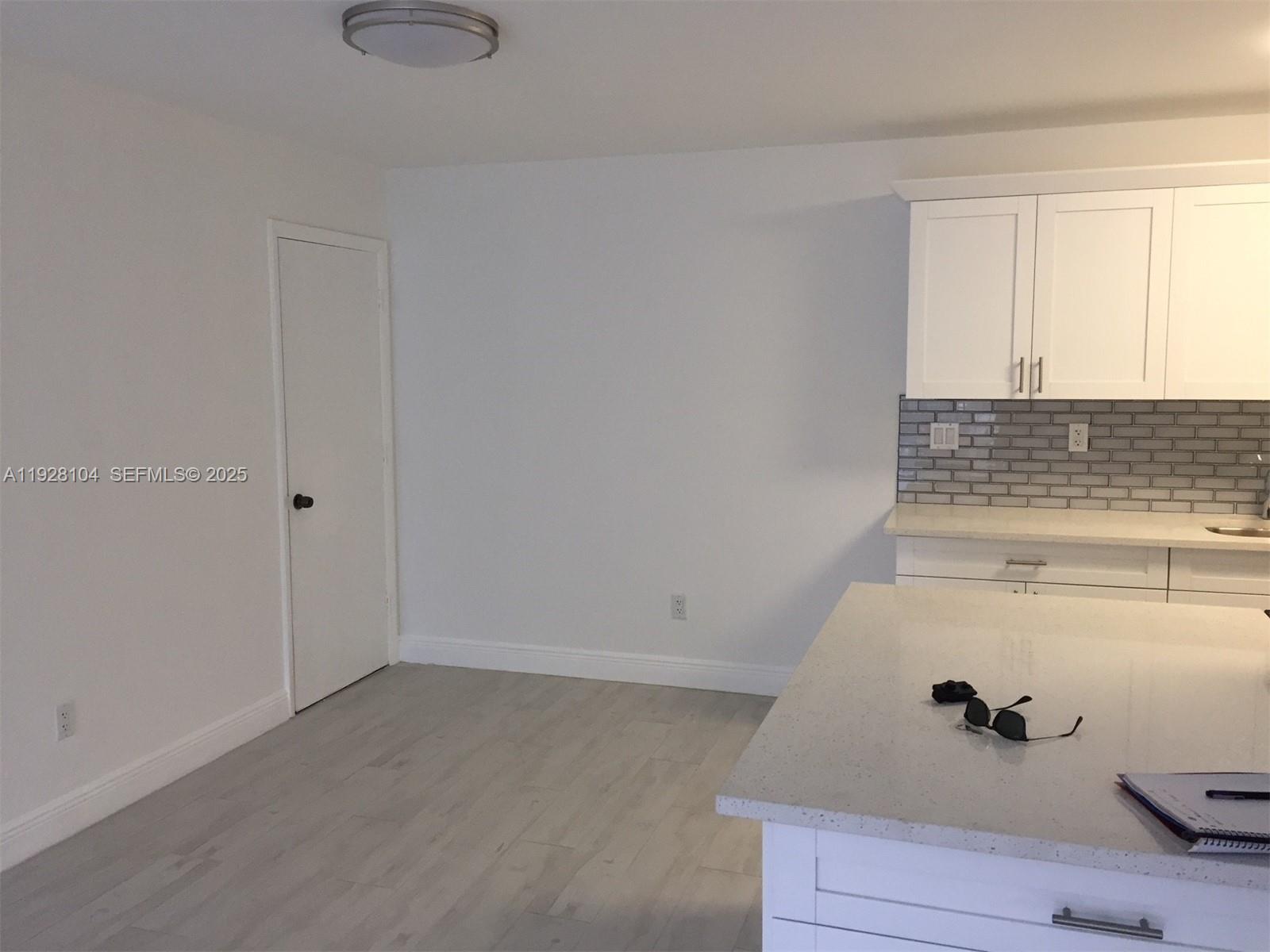 A kitchen features white cabinets, a gray subway tile backsplash, and a light-colored island — 10740 N Kendall Dr # 24, Miami FL 33176, MIAMI, FL