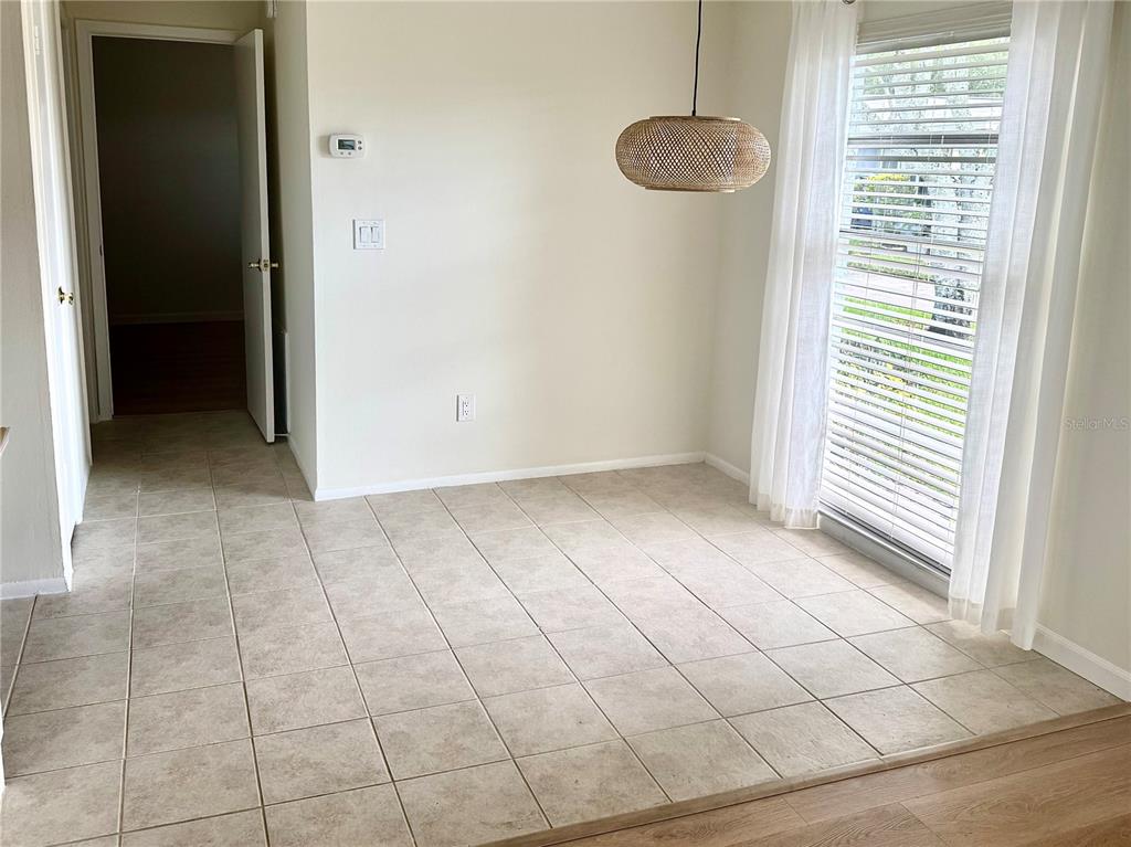 A dining area features beige tile flooring, a woven pendant light, and a large window — 1610 BERWICK COURT UNIT D, PALM HARBOR, FL