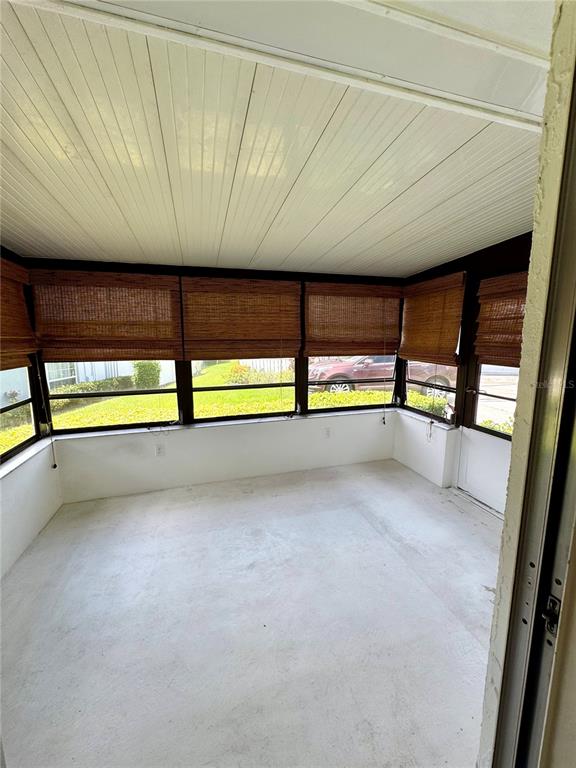 An enclosed porch features white walls, a paneled ceiling, and bamboo roll-up shades — 1610 BERWICK COURT UNIT D, PALM HARBOR, FL