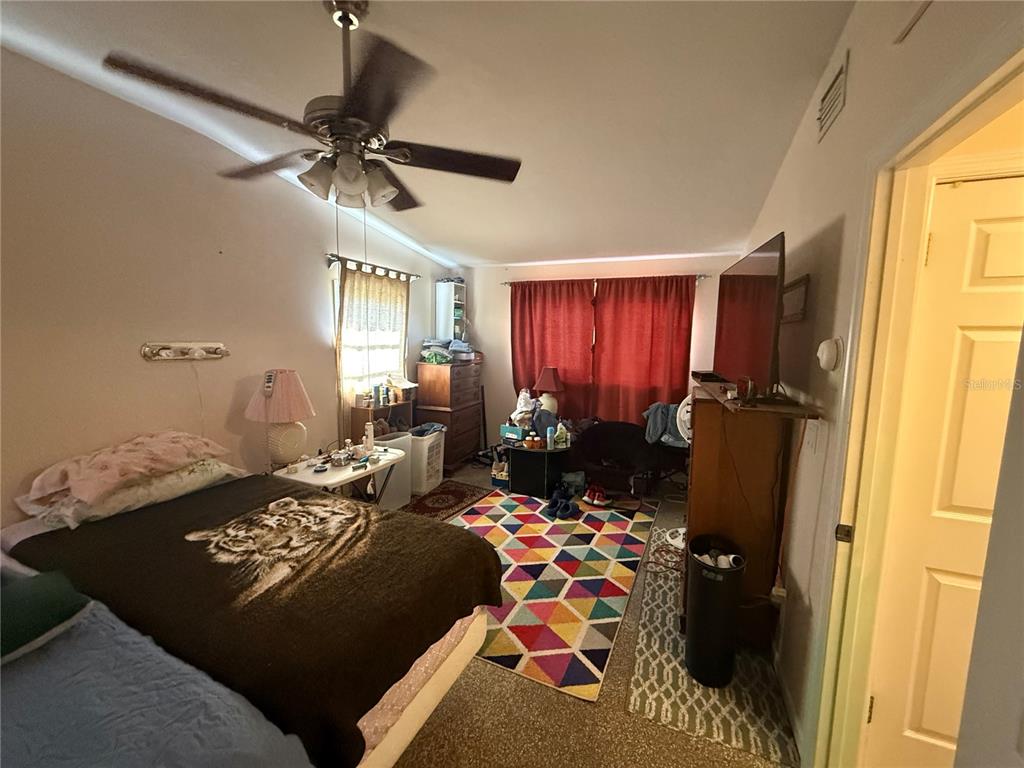 A bedroom features a bed with a tiger-print blanket, a colorful rug, and a ceiling fan — 202 FAIRMONT DRIVE, SANFORD, FL