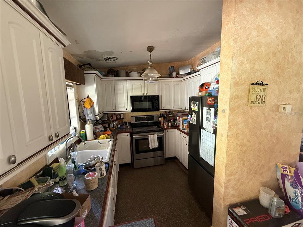 A kitchen features white cabinetry, stainless steel appliances, a double sink, and a textured ceiling — 202 FAIRMONT DRIVE, SANFORD, FL