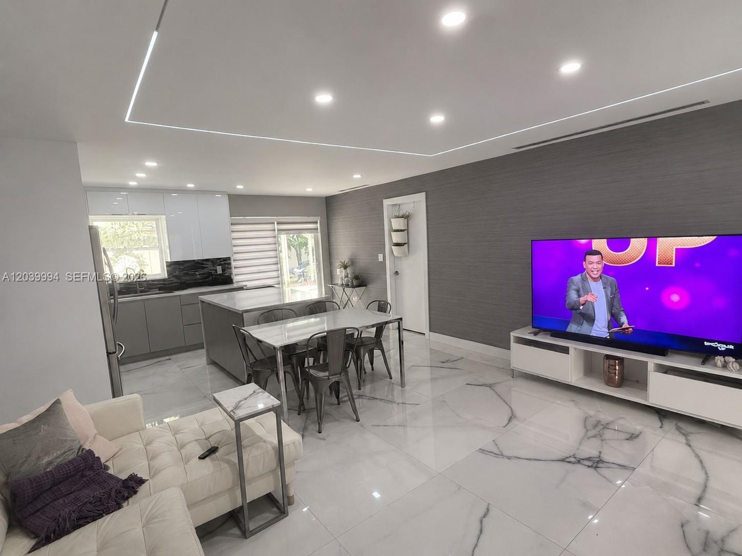 A modern open-concept living room and kitchen featuring marble-look tile floors and recessed lighting — 7521 Shalimar St, Miramar FL 33023, MIRAMAR, FL