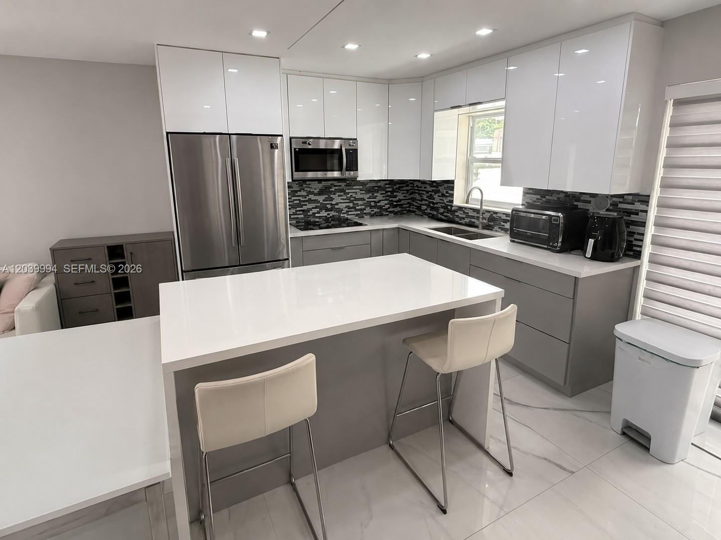 A modern kitchen features white upper cabinets, gray lower cabinets, and a white island — 7521 Shalimar St, Miramar FL 33023, MIRAMAR, FL