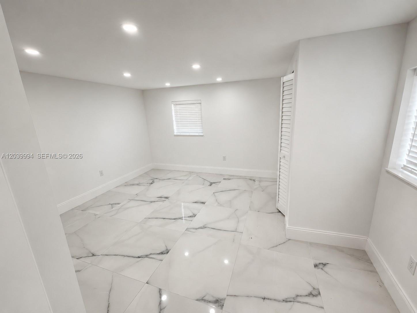 An empty room features white walls, recessed lighting, and large white marble-patterned floor tiles — 7521 Shalimar St, Miramar FL 33023, MIRAMAR, FL