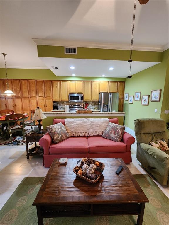 An open-concept living room features a red sofa, wooden coffee table, and adjacent kitchen area — 400 RAVINIA CIRCLE UNIT 400, VENICE, FL