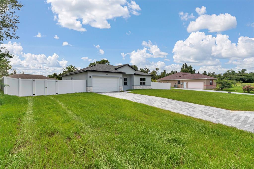 A modern single-story house with a paved driveway and white vinyl fencing — 3888 SW 157TH PLACE ROAD, OCALA, FL