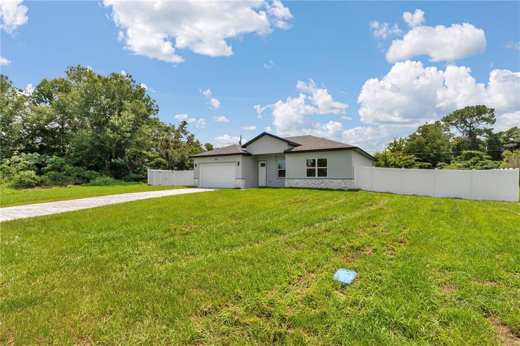 A single-story house with a white garage and stone accents sits on a grassy lot — 3888 SW 157TH PLACE ROAD, OCALA, FL