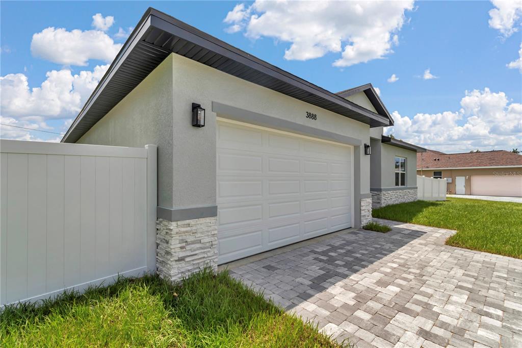 A view of a house exterior featuring a white garage door and stone accents — 3888 SW 157TH PLACE ROAD, OCALA, FL