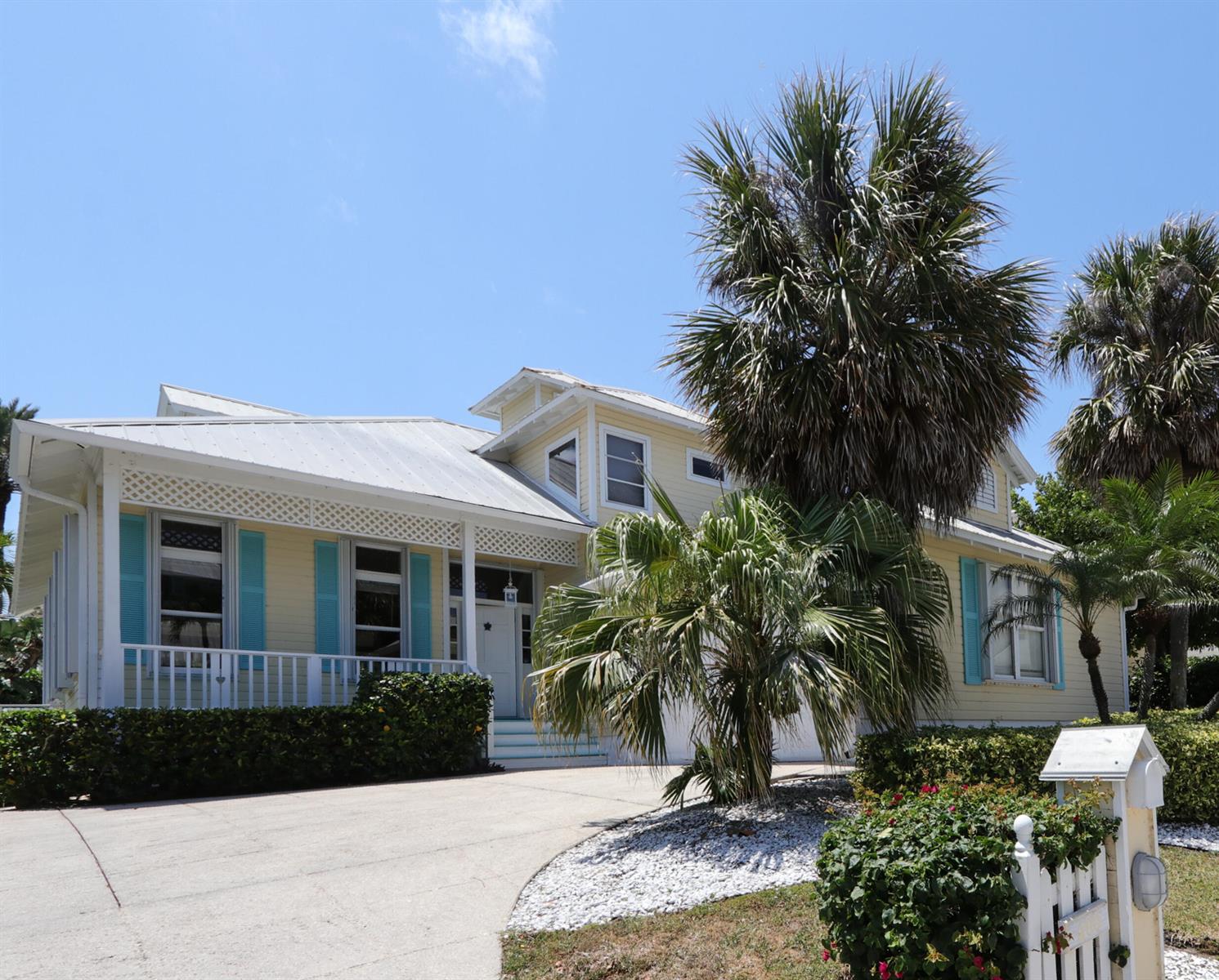 A yellow house with a metal roof, turquoise shutters, and a palm tree in front — 400 Seaside Lane, Juno Beach FL 33408, JUNO BEACH, FL