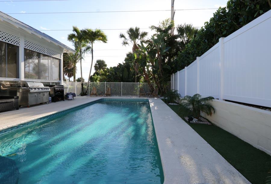 A backyard swimming pool with a patio, grill, and white privacy fence — 400 Seaside Lane, Juno Beach FL 33408, JUNO BEACH, FL
